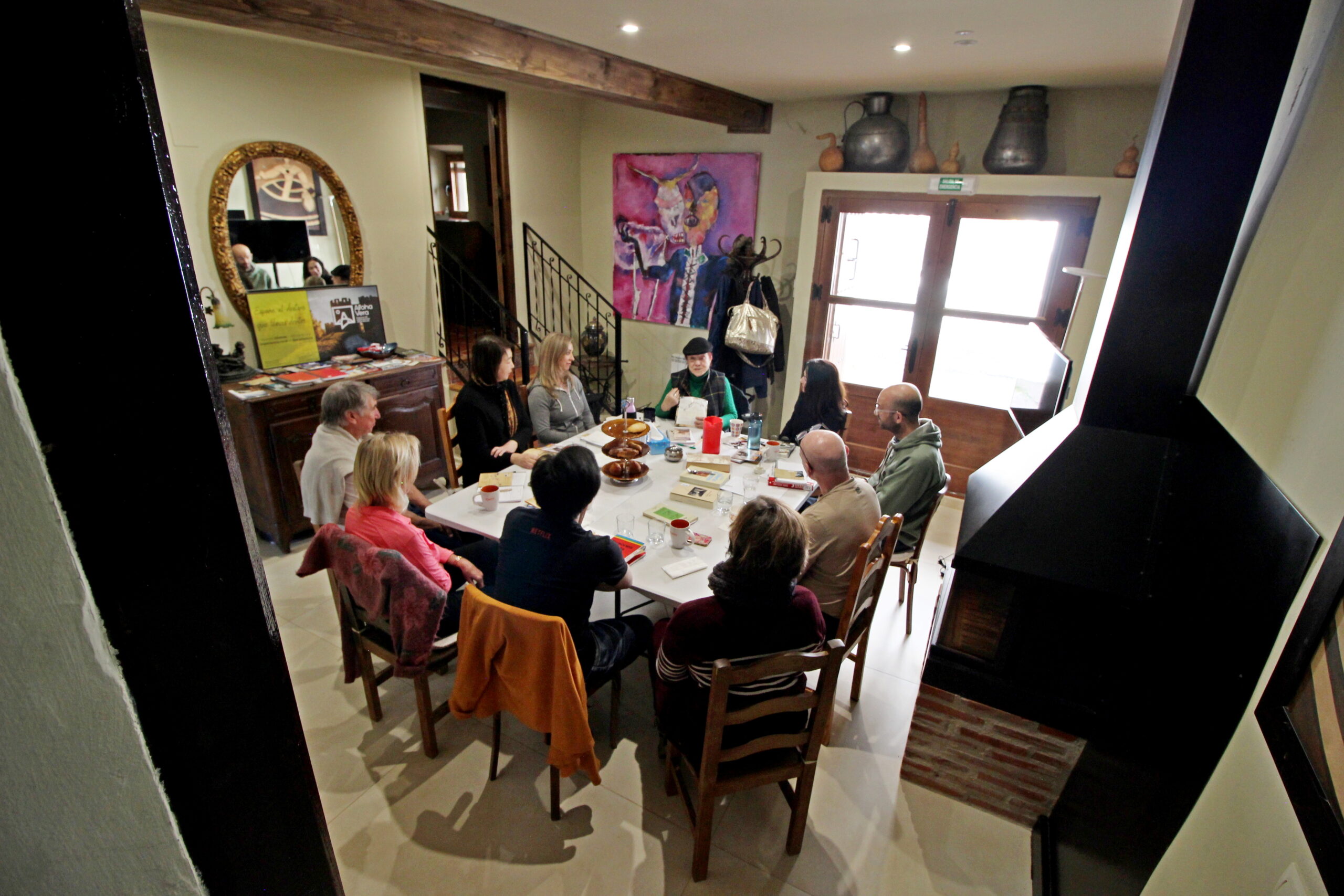 Gente reuniéndose alrededor de una mesa en interior.