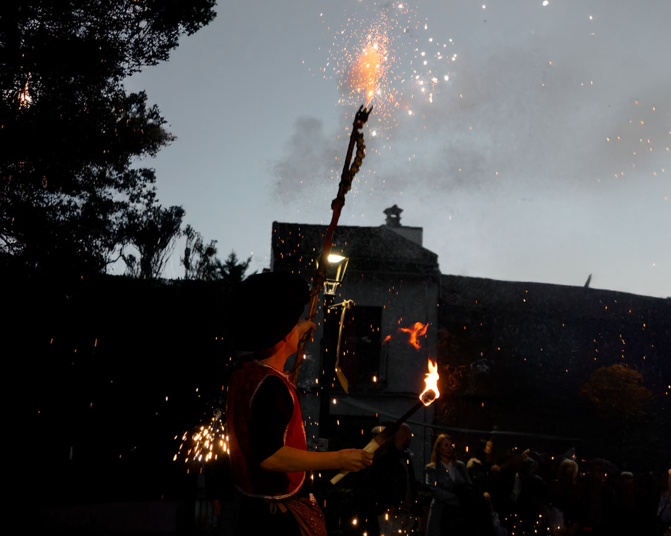 Performer holding fireworks torch at dusk outdoors