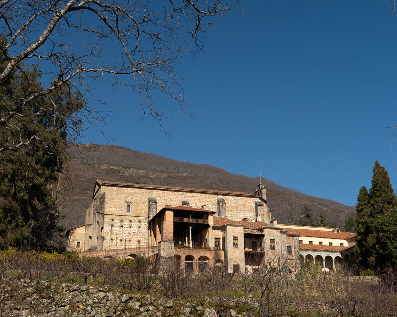Historic stone monastery on hillside under blue sky