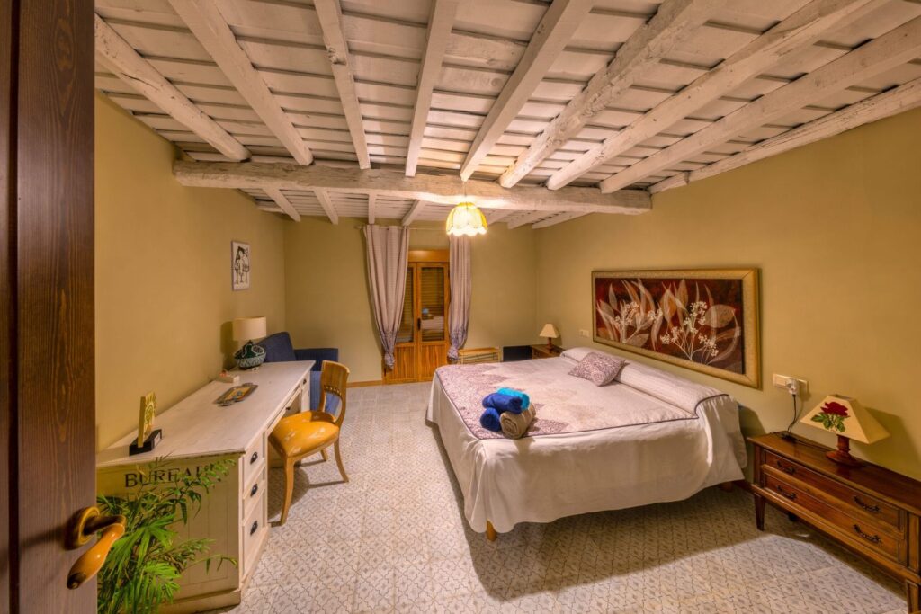 Bedroom with a beamed ceiling, a desk and a double bed