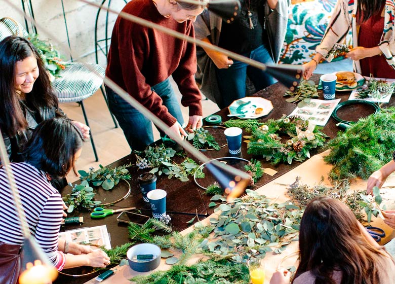 Un groupe faisant des couronnes avec de la verdure fraîche autour d'une table d'atelier